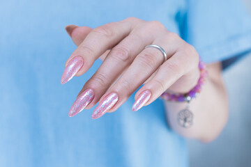 Woman's hands with long nails and a light pink color nail polish