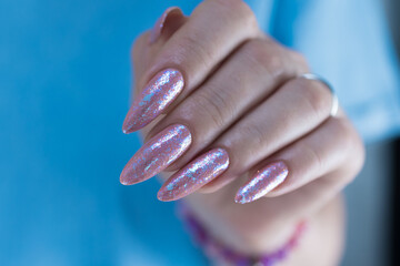 Woman's hands with long nails and a light pink color nail polish