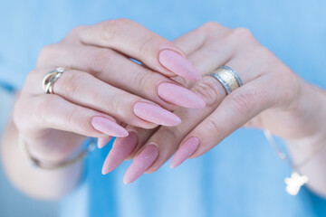 Woman's hands with long nails and a light pink color nail polish