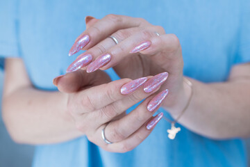 Woman's hands with long nails and light pink color nail polish