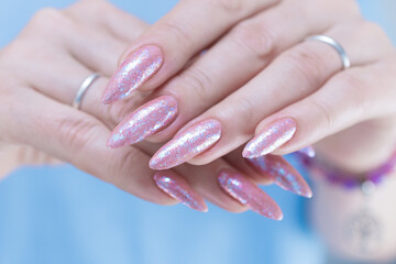 Woman's hands with long nails and light pink color nail polish