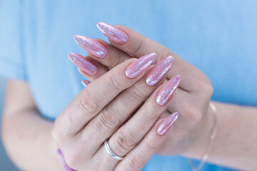Woman's hands with long nails and light pink color nail polish