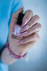 Woman's hands with long nails and a light pink color nail polish