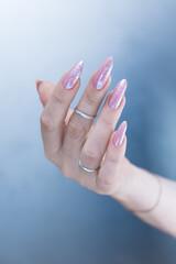 Woman's hands with long nails and a light pink color nail polish