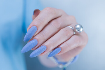 Woman's beautiful hand with long nails and light baby blue manicure	