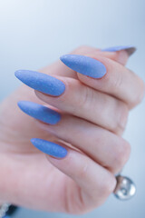 Woman's beautiful hand with long nails and light baby blue manicure	