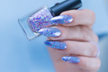Female hand with long nails and bright light blue and silver manicure	