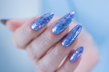 Female hand with long nails and bright light blue and silver manicure	