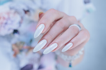 Woman's hands with long nails and a light white color nail polish
