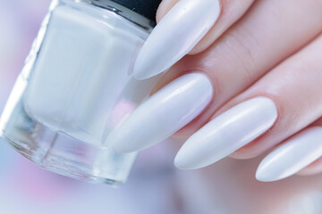 Woman's hands with long nails and a light white color nail polish