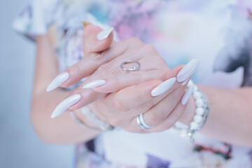 Woman's hands with long nails and a light white color nail polish