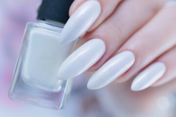 Woman's hands with long nails and a light white color nail polish