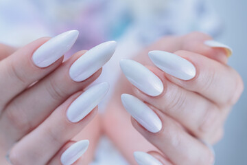 Woman's hands with long nails and a light white color nail polish