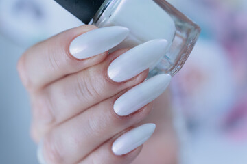 Woman's hands with long nails and a light white color nail polish