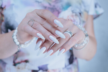 Woman's hands with long nails and a light white color nail polish