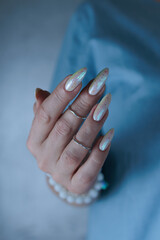 Woman's hands with long nails and a light white color nail polish