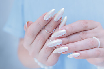 Woman's hands with long nails and a light white color nail polish