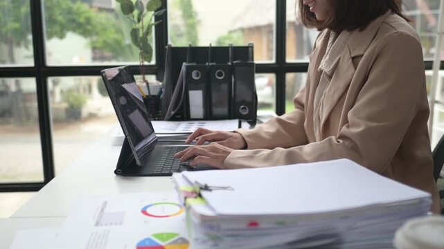 Productive businesswoman typing on laptop at office desk with paperwork