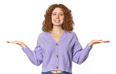 Young Caucasian redhead woman makes scale with arms, feels happy and confident.