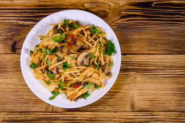 Pasta with mushrooms and tomato sauce in a plate. Top view
