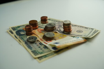 Several dollar, euro and yen bills surrounded by coins of different currencies as a concept of foreign exchange purchase