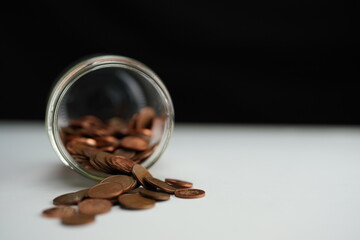 Overview of coins of different currencies coming out of a jar lying on its side