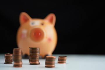 coins of different currencies in front of a piggy bank out of focus in the background as a savings concept