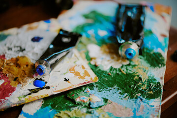 Closeup shot of opened acrylic paint tubes lying on palettes at artists workplace