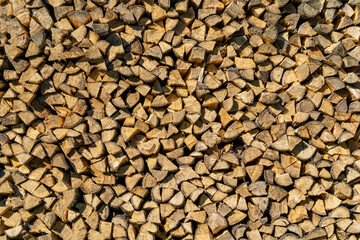 Firewood storage concept. Natural sawn wood stacked in row, texture. Stacks of chopped logs as background. Romantic winter in front of fireplace. Wallpaper.