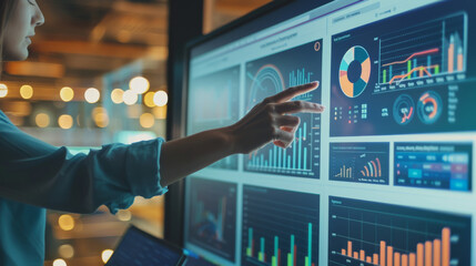 A person points toward colorful statistical charts on a large screen in a modern office, illustrating data analysis and team collaboration.