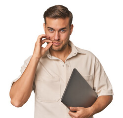 Man holding laptop, studio with fingers on lips keeping a secret.