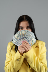  business woman wear yellow suit holding dollar money isolated on grey