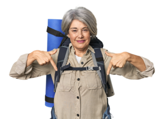 Caucasian mid-age female with hiking gear points down with fingers, positive feeling.