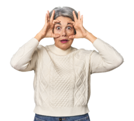 Caucasian mid-age female on studio background keeping eyes opened to find a success opportunity.