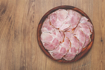 sliced pork neck, boiled and smoked, smoked pork neck, sliced, on a wooden chopping board, close-up,