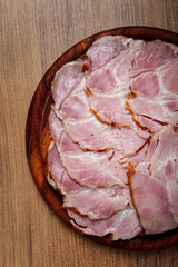 sliced pork neck, boiled and smoked, smoked pork neck, sliced, on a wooden chopping board, close-up,
