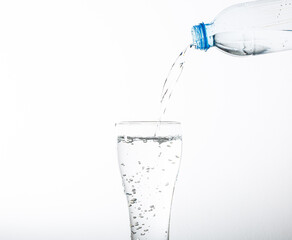 Pouring drinking water into a glass, isolated on white background. Plastic water bottle and pouring water into a glass, isolated on white background.