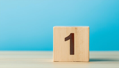 Wooden cube with number 1 one on wooden table with blue wall on background. Close-up.