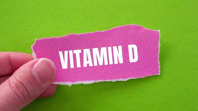 Vitamin d message writing on ripped torn pink paper piece on green background