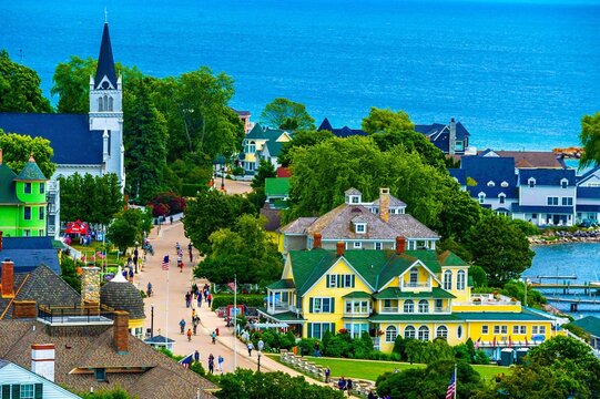 Scenic view of Mackinac Island with colorful houses, a church, and people walking along the street