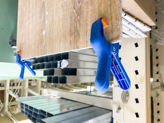 In the busy store, a blue clamp secures a large timber piece, enabling customers to admire and...