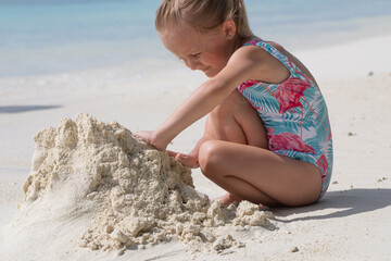 A girl plays with sand, a child builds a castle from sand