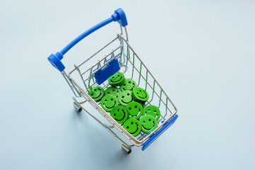 Shopping cart with smiles. Buying positive emotions or happiness, shopaholism.