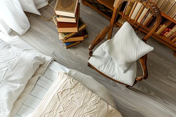Overhead view of a cozy bedroom with a comfortable chair, a stack of books, and a bed with white linens.