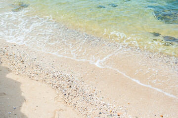 Soft blue ocean wave on clean sandy beach with rocks and splashing waves,Summer vibe on holiday vacation.