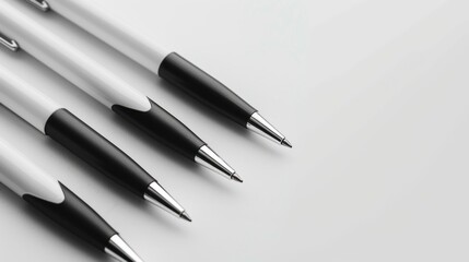 White and black pens on a table. Four pens, with white barrels and black caps, are laid out in a row on a white surface.