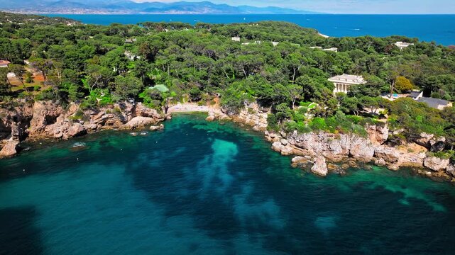 View from above of Billionaire Bay and rocky beach near coastal path on the Cap Antibes. Aerial view of the picturesque bay with luxurious villas, breathtaking views, and crystal-clear waters on Frenc