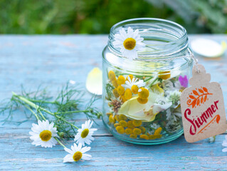 Summer mood concept. Flowers in a jar with a summer tag on a blue wooden table. Bright and festive...