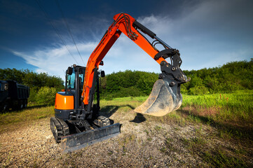 bulldozer stands on a piece of land against the backdrop of a bright blue sky and green trees. construction equipment ready to work