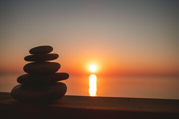 A cairn of stones against the background of a sunset or an entrance to the sea
